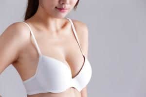 Closeup view of a young woman body chest breast with bra isolated on gray background, asian beauty