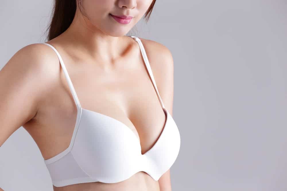 Closeup view of a young woman body chest breast with bra isolated on gray background, asian beauty