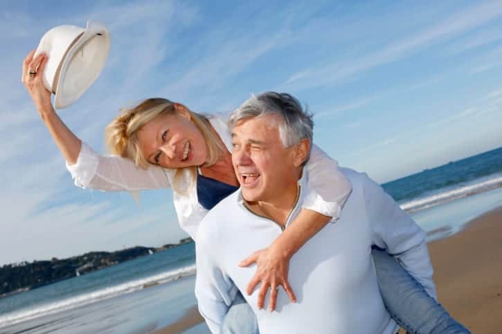 Senior man carrying wife on beach