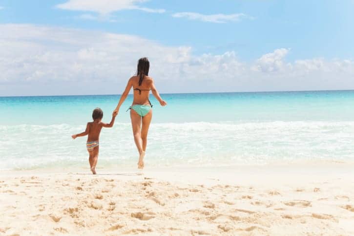 Child and woman running to the sea holding hands